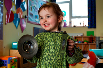 A young child holding a pair of cymbals